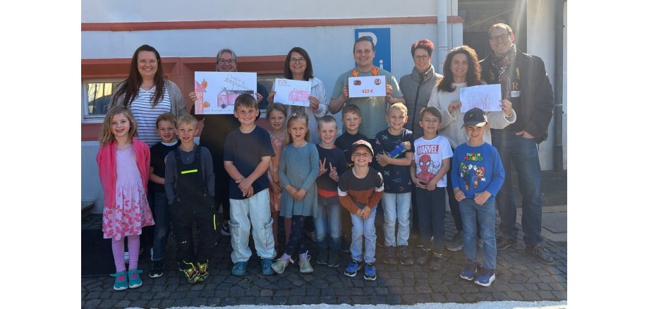 Bild mit Kita-Kindern, die eine Spende an Bürgermeistern und Gemeindebrandinspektor übergeben