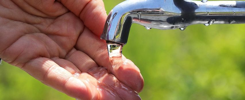 Hand und Wasserhahn aus einem Wasserhahn läuft Wasser in die geöffnete Hand