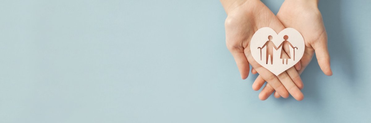 Hand mit Holzherz Offene Handfläche, die ein Holzherz hält, aus dem ein Mann und eine Frau ausgestanzt sind, die jeweils einen Spazierstock halten.