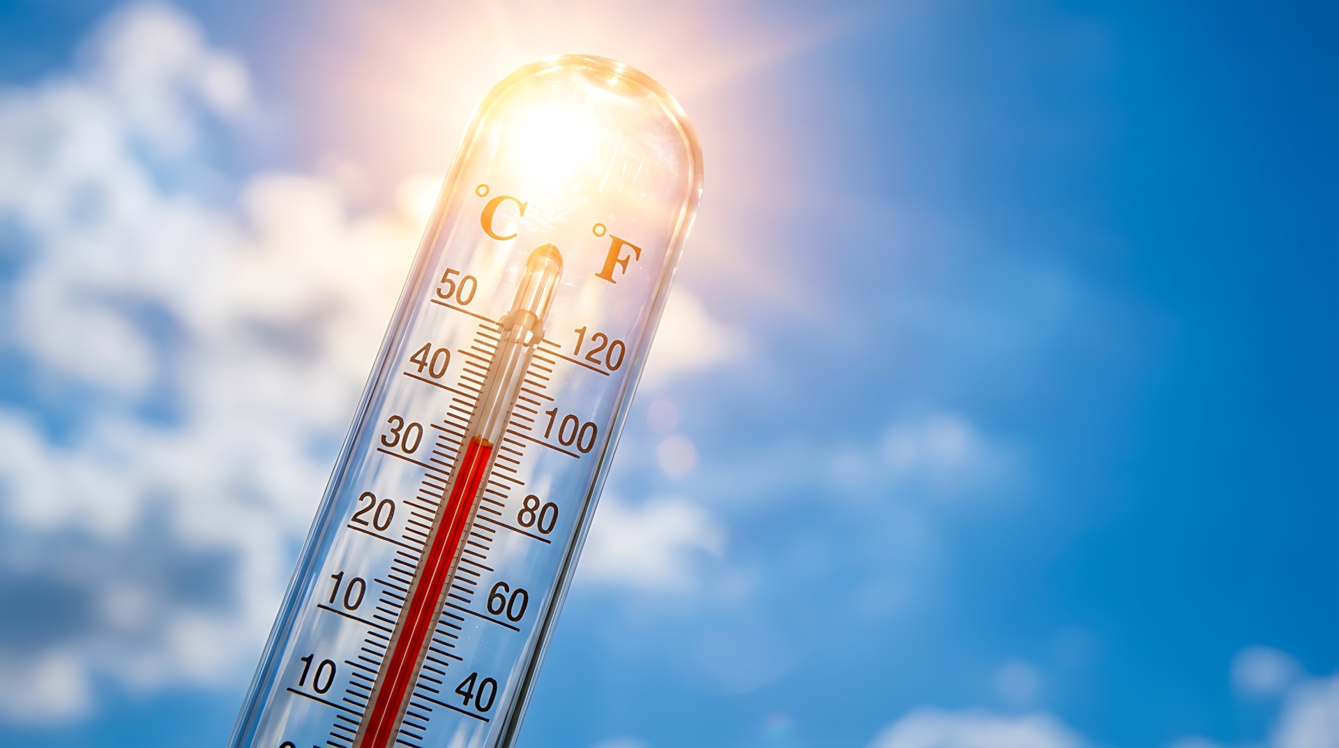 Ein analoges Thermometer zeigt über 30 Grad an, im Hintergrund sieht man die Sonne und den blauen Himmel