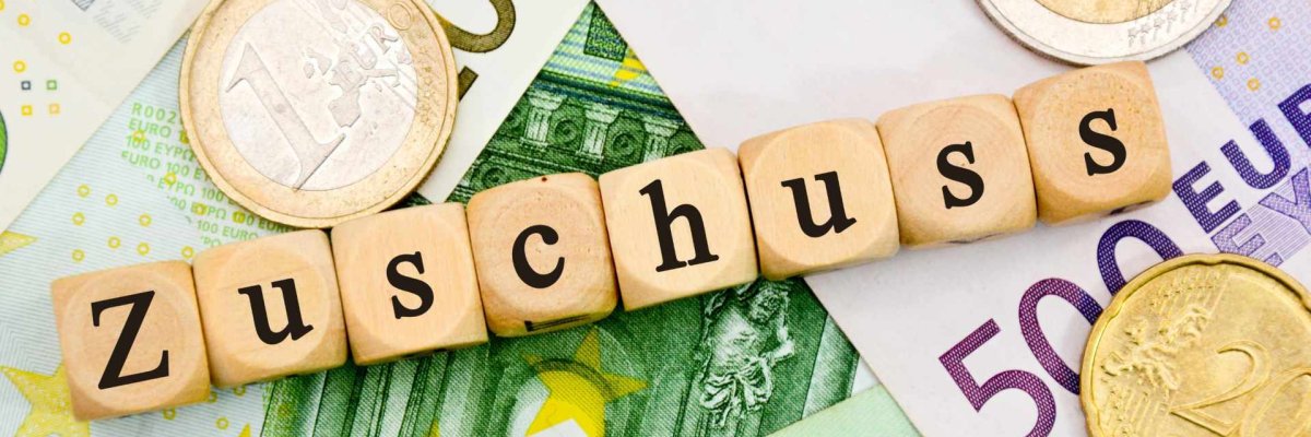 Vereinsförderung Geldmünzen, Geldscheine sowie das Wort Zuschuss in Scabblebuchstaben gelegt.